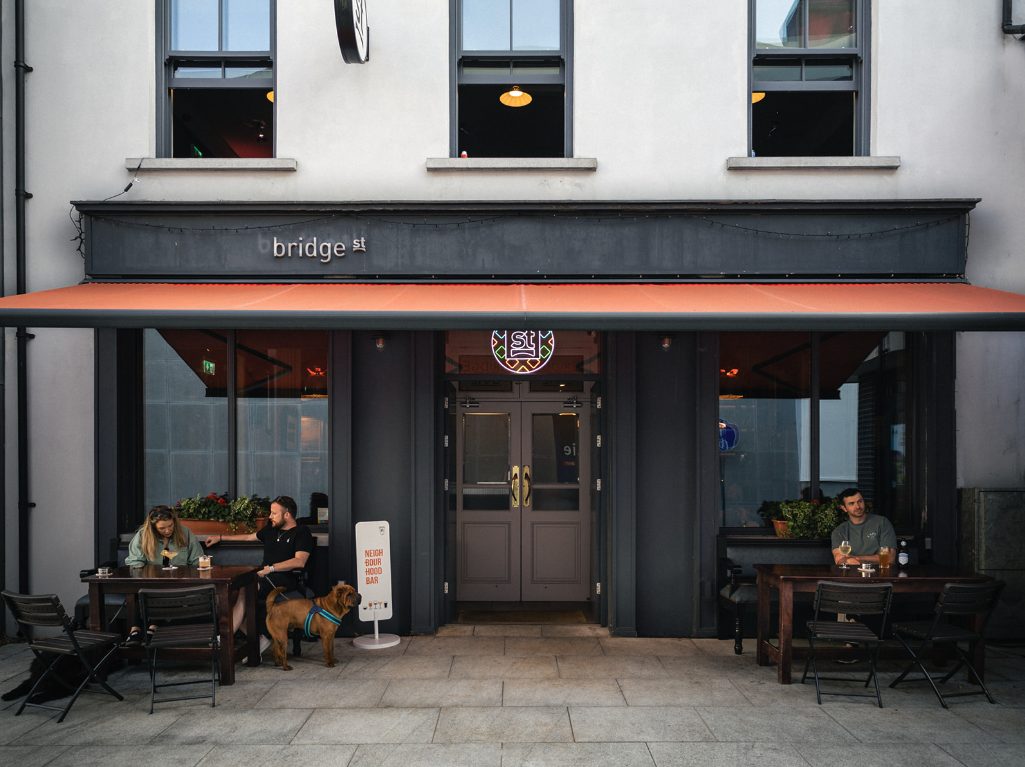 The exterior under the orange awning, outdoor tables set